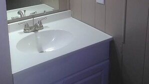 Ein Badezimmer mit einem weißen Waschbecken, einem Spiegel und drei Deckenleuchten.