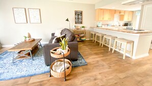 A modern living room with a sofa, coffee table, and a dining area with a kitchen in the background. - Cozy 2BR Lake Monroe Golf Condo IU Bloomington (Bloomington)
