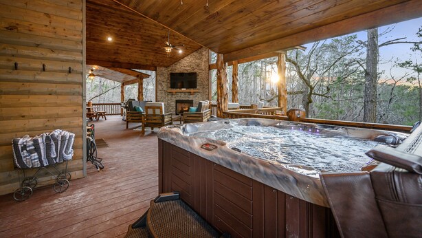 L’intérieur d’un chalet en bois comprend un bain à remous, une terrasse en bois et une cheminée en pierre.