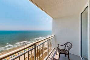 A balcony with a view of the beach and ocean.