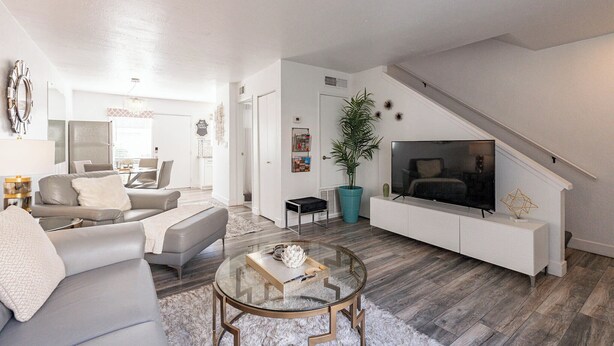 A modern living room with a sofa, coffee table, and a TV on a white console.