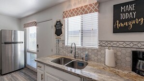 A modern kitchen with a stainless steel refrigerator, double sink, and a coffee maker.