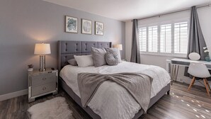 A bedroom with a bed, bedside tables, a desk, and a window with curtains.