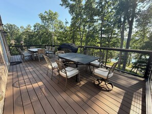 A wooden deck with a table and chairs, surrounded by trees and a view of a body of water. - Falcons Crest at Sequoyah Marina (Norris Lake) (Andersonville)