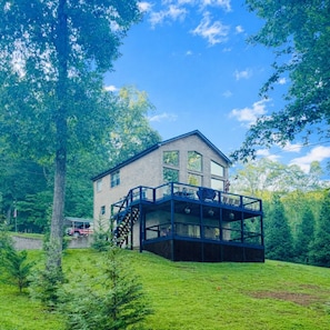 Ein modernes Haus mit einer großen Terrasse, umgeben von üppigem Grün.