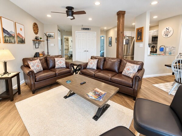 A living room with a brown leather sofa set, a coffee table, and a ceiling fan.