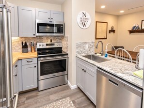 A modern kitchen with stainless steel appliances, a granite countertop, and a backsplash.