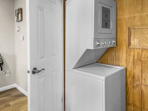 A compact laundry room with a built-in washer and dryer, a white door, and a wooden wall.