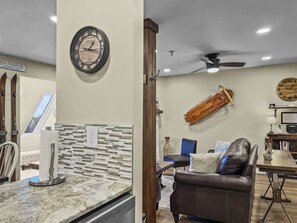 A living room with a leather sofa, a dining table, and a kitchen area with a marble countertop.