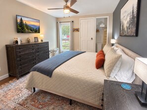 A bedroom with a bed, dresser, and a ceiling fan.