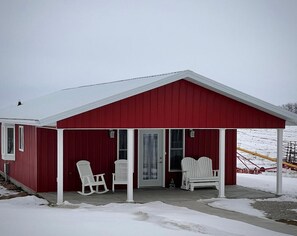 A red building with a covered porch and two rocking chairs. - Little Country House a Quiet Countryside Getaway! (Newton)