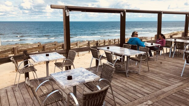 An outdoor seating area with tables and wicker chairs overlooking the ocean. - VILLA BIDAOUS 4*-heated pool, table tennis, 3 bicycles, real table football-Messanges (Messanges)
