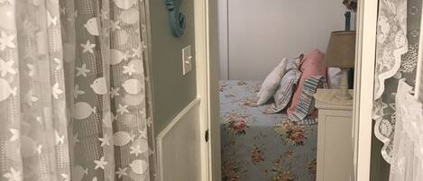 A bathroom with a shower curtain, a bed with floral bedding, and a 'RELAX' sign on the wall.