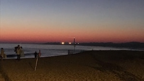 A beach at dusk with a pier in the background.