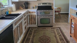 Una cocina con armarios de madera, una estufa de acero inoxidable, un microondas y un tapete grande.