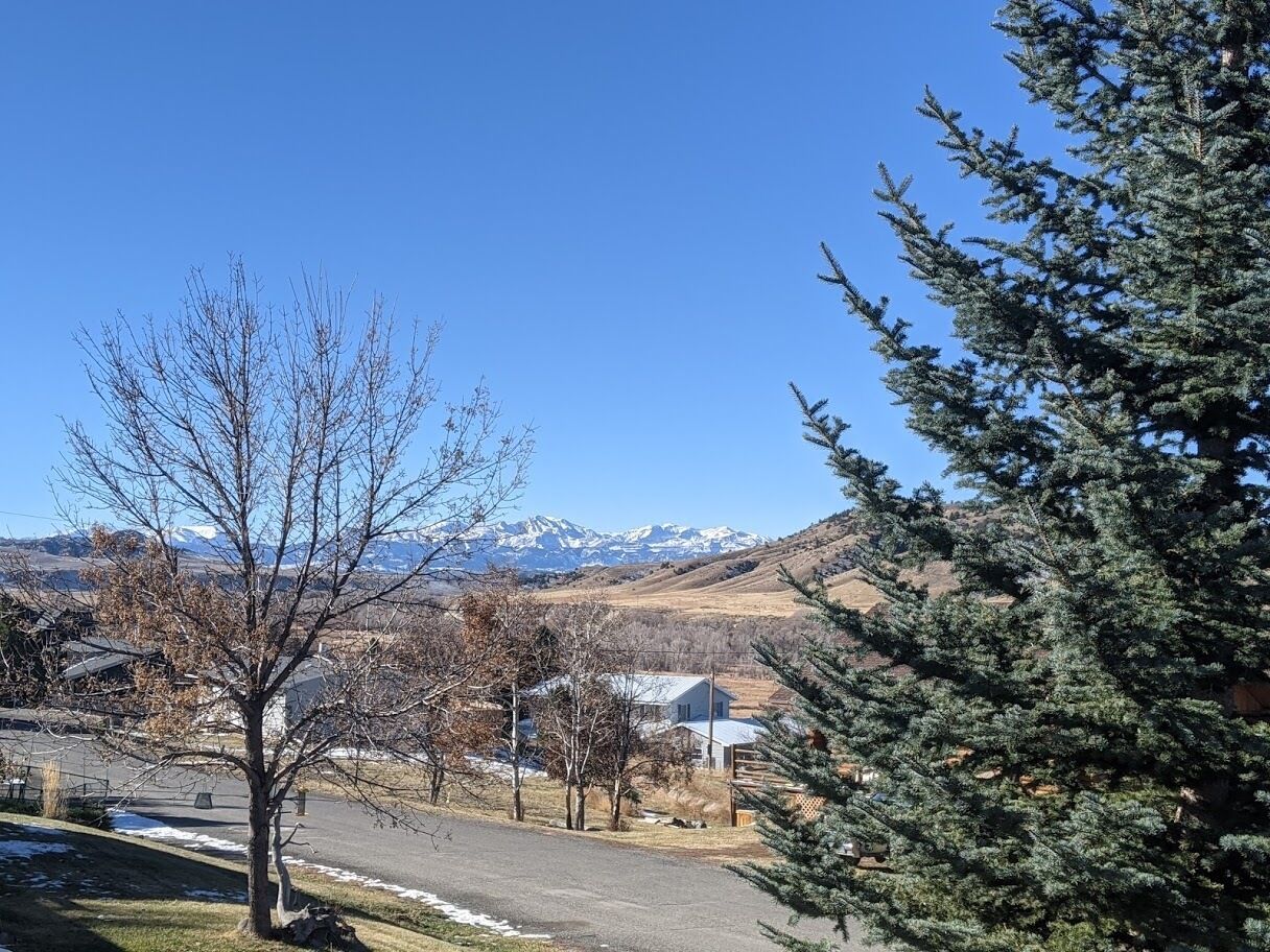Un barrio residencial con casas, cielo despejado y una cordillera en el fondo.