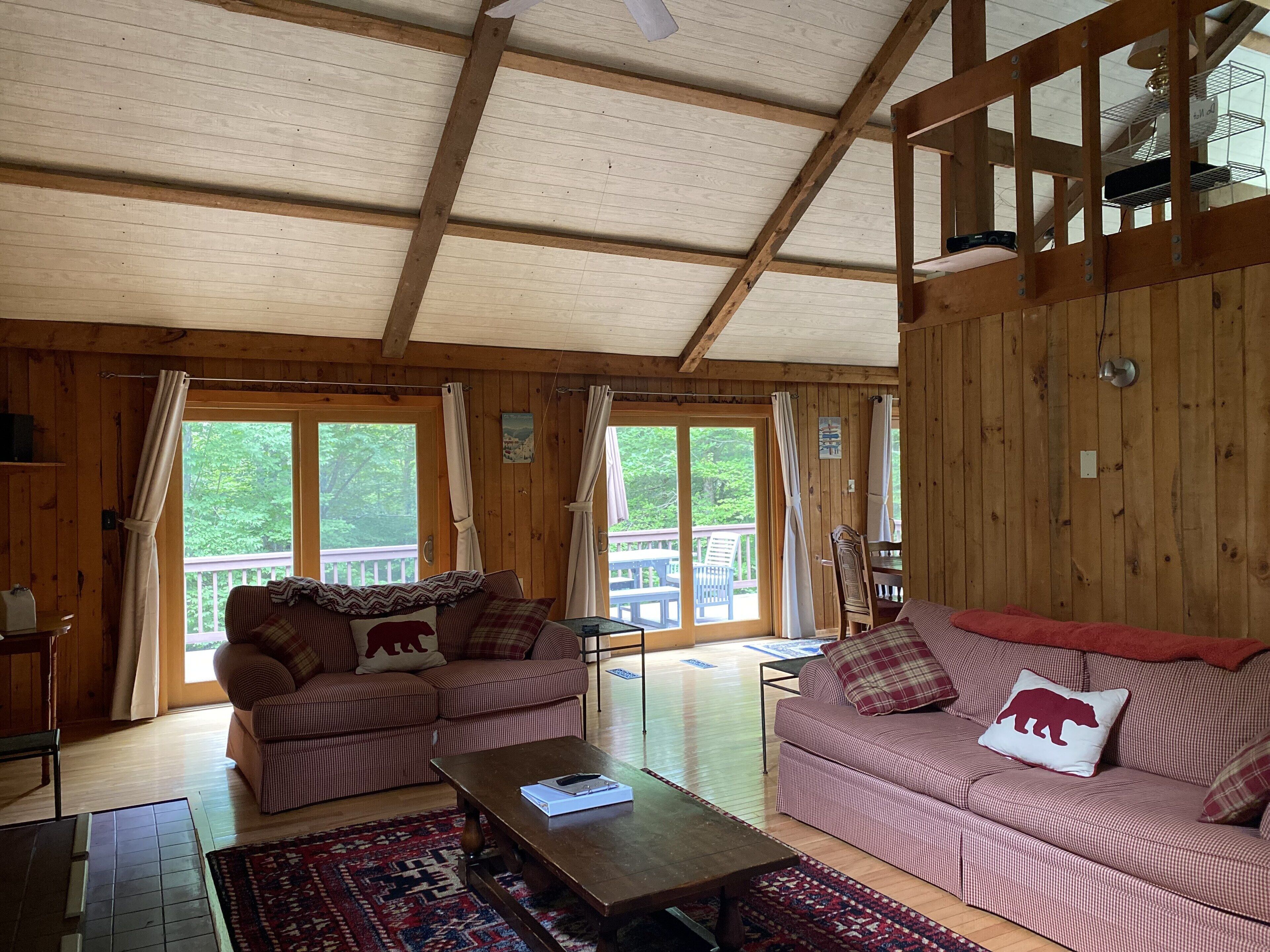 Interior acogedor de una cabaña con dos sofás, una mesa de centro de madera y un ventanal grande.