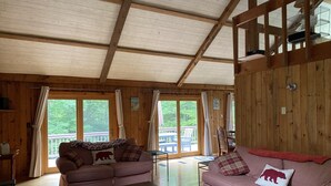 A cozy cabin interior with two sofas, a wooden coffee table, and a large window. - White Mountain Retreat, Waterville Estates Amenities  (Campton)