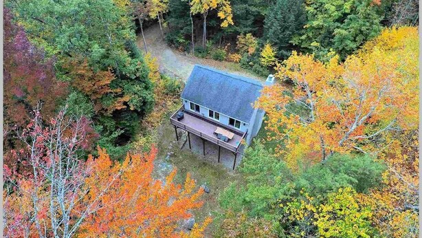 A house with a porch, surrounded by autumn foliage. - White Mountain Retreat, Waterville Estates Amenities  (Campton)