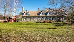 A large stone house with multiple chimneys, a stone foundation, and a grassy yard. - Beautiful Historic Country Estate – Modern Comfort in Okemo Valley (Cavendish)