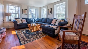A living room with a sectional sofa, a wooden coffee table, and a patterned rug. - Beautiful Historic Country Estate – Modern Comfort in Okemo Valley (Cavendish)