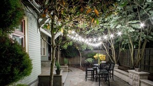 A patio area with stone flooring, a table with chairs, and string lights.