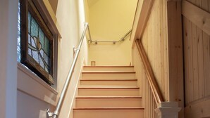 A wooden staircase with white railings and a handrail, leading to a landing with a glass door.
