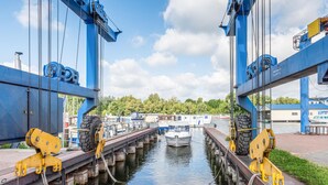 En kanal med en förtöjd båt, omgiven av industriella byggnader och grönska.