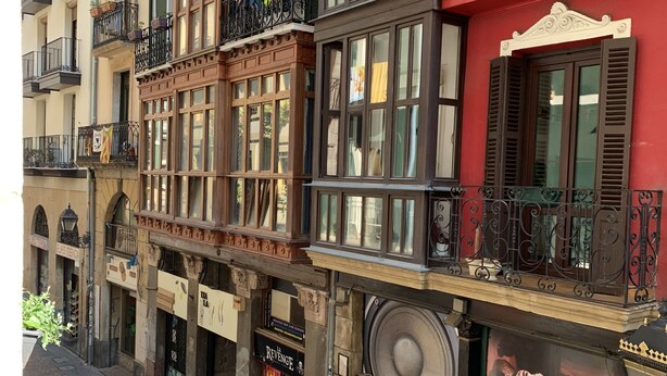 A multi-story building with balconies, storefronts, and a variety of signage.