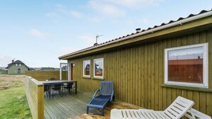 A wooden deck with a table and chairs, a blue chair, and a white lounge chair. - Gorgeous home in Harboøre with WiFi (Harboøre)