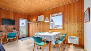 A cozy room with wooden walls, a dining table with chairs, a TV, and a window with a view. - Gorgeous home in Harboøre with WiFi (Harboøre)