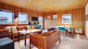 A cozy cabin interior with wooden walls, a dining area, and a living space with a sofa and chairs. - Gorgeous home in Harboøre with WiFi (Harboøre)