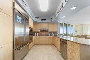 Une cuisine moderne dotée d’appareils électroménagers en acier inoxydable, de meubles en bois et d’une grande fenêtre offrant une vue dégagée.