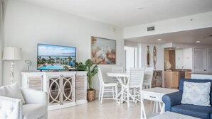 A modern living room with a television, dining area, and kitchen.