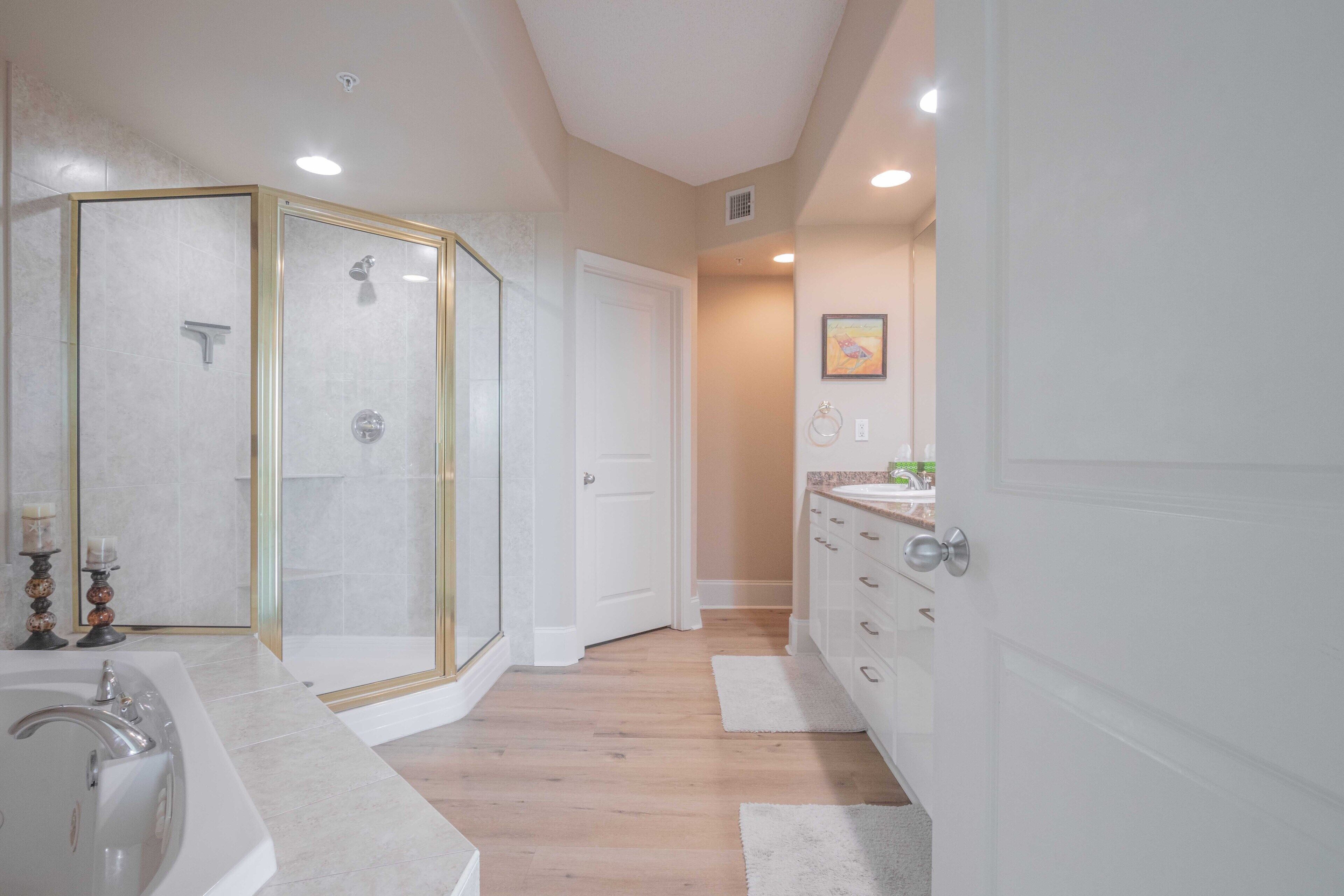 A bathroom with a glass-enclosed shower, a bathtub, and a vanity with drawers.