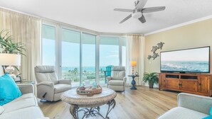 Un salón amplio con televisor grande, asientos cómodos y un balcón con vistas.