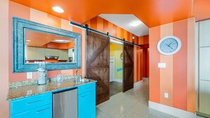 A kitchen with blue cabinets, a stainless steel dishwasher, and a large mirror above the counter. - Luxurious Caribe 4BR/3BA Beach View Condo (Orange Beach)