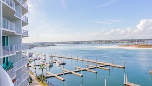 Et højt hotel med altaner der kigger ud over en lystbådehavn med både og en sandstrand i det fjerne.