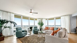A spacious living room with a large window, a ceiling fan, and a view of the outdoors.