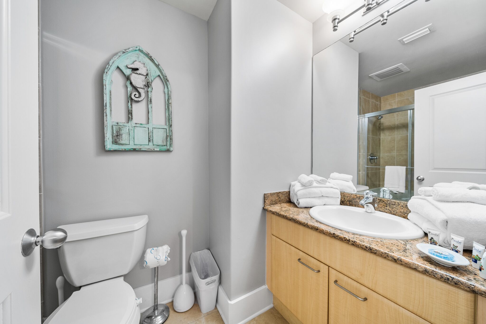 Une salle de bain comprenant des toilettes, un lavabo, un meuble-lavabo et un miroir.