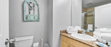 Une salle de bain comprenant des toilettes, un lavabo, un meuble-lavabo et un miroir.