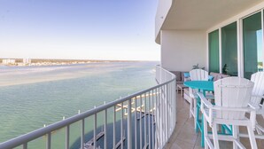 Ein Balkon mit Blick auf das Wasser, weißen Stühlen und einem Tisch.