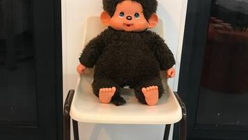 A plush toy seated on a white chair with a black frame.
