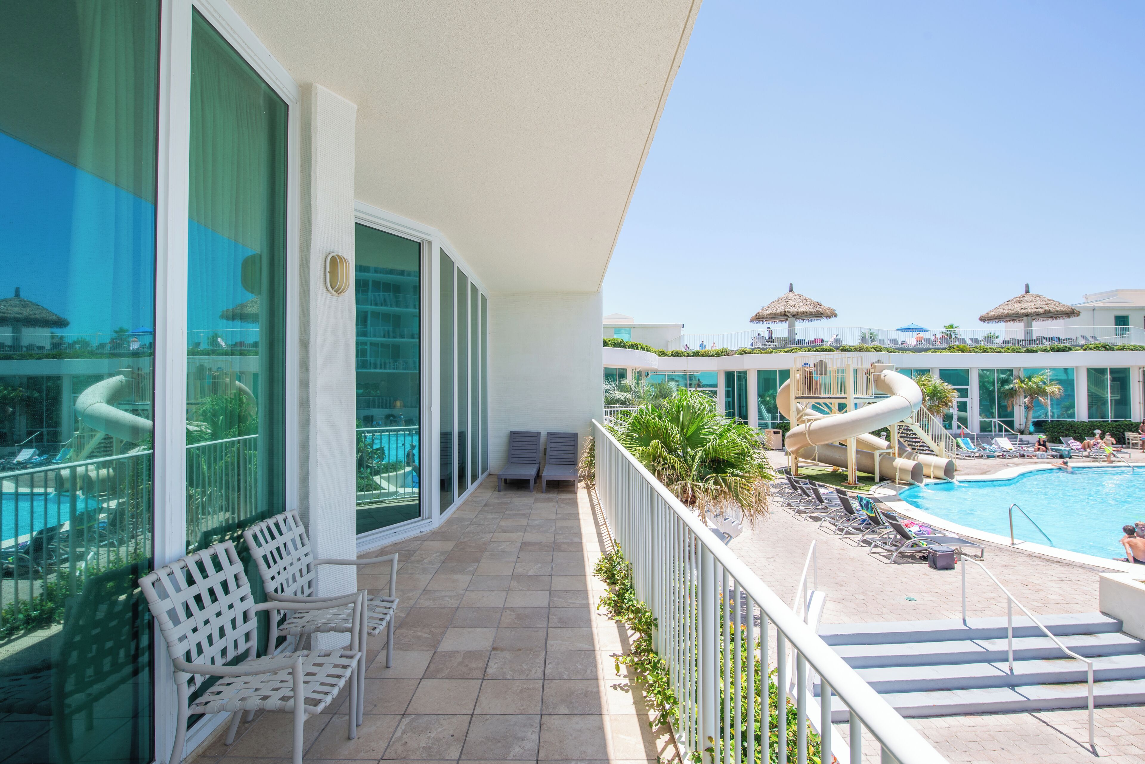 A balcony with a pool, lounge chairs, and a water slide.