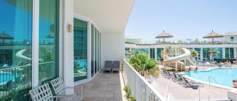 A balcony with a pool, lounge chairs, and a water slide.