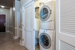 A laundry room with two stacked front-loading washing machines and a dryer.