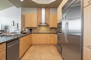 Una cocina moderna con armarios de madera, electrodomésticos de acero inoxidable y salpicadero de azulejos.