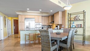 A spacious kitchen with a central island, wooden cabinets, and a dining area with wicker chairs. - Three Bedroom Condo with Calming Bay Views! Complimentary Boat Slip! Message about Spring Special (Orange Beach)