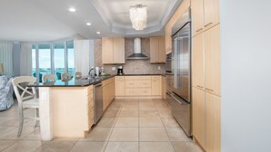Een moderne keuken met een centraal eiland, roestvrijstalen apparatuur en uitzicht naar buiten.