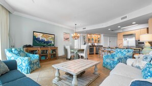 Un soggiorno spazioso con una grande TV, un'area pranzo e una cucina con mobili in legno.